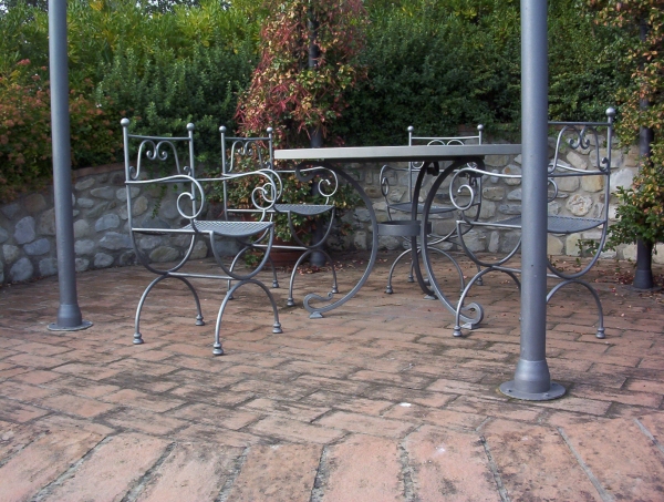 Gazebo in ferro con tavolo e sedie. Il gazzebo si colloca nel giardino di una villa sulle colline di Lajatico. Le sedie e il tavolo sono in ferro battuto, decorate con riccioli.